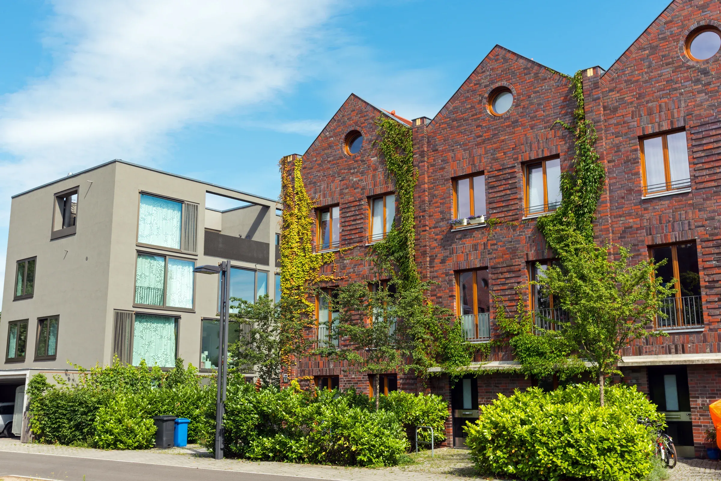Moderne Wohnhäuser mit Klinkerfassade und Grün an einer ruhigen Straße